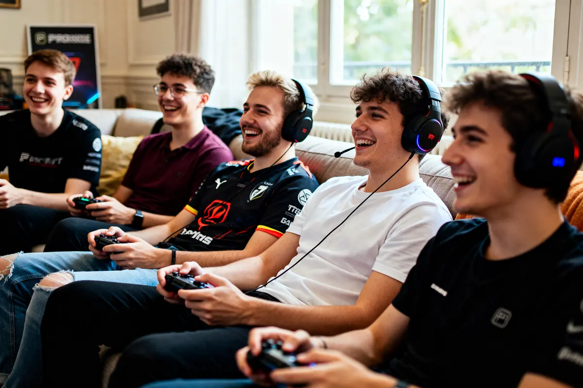 Cinq jeunes hommes souriants jouent ensemble aux jeux vidéo, connectant les gamers autour d'eux